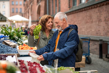 Ein glückliches älteres Touristenpaar kauft auf dem Markt in der Stadt Obst. - HPIF06739