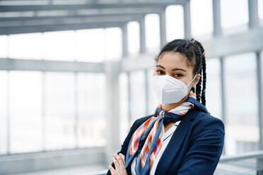 Porträt einer jungen Stewardess mit Blick in die Kamera in einer Flughafenlounge, Coronavirus, Reisen und neue Normalität. - HPIF06831