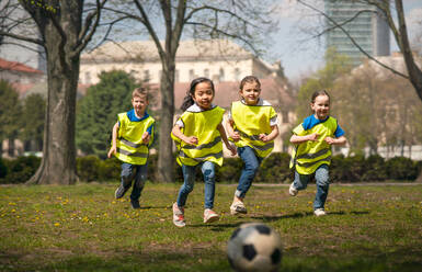 Glückliche kleine Kinder spielen Fußball im Freien im Stadtpark, Lerngruppe Bildungskonzept. - HPIF06879