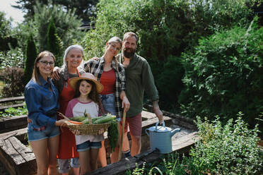 Eine glückliche Bauernfamilie schaut in die Kamera und hält ihre Ernte im Garten. - HPIF06901