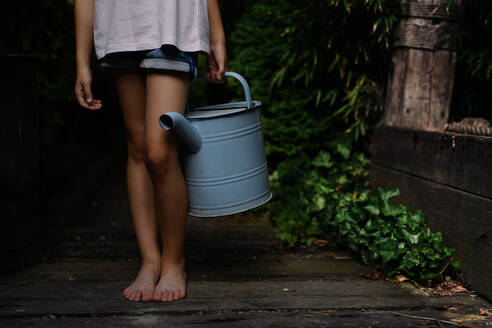 Niedriger Ausschnitt eines kleinen Mädchens in Shorts, das eine Gießkanne im Freien im Garten hält. - HPIF06912