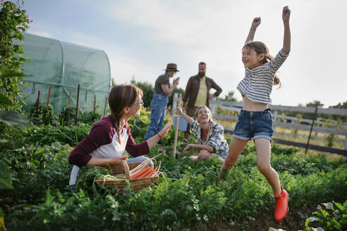 Happy young and old farmers or gardeners working outdoors at a community farm. - HPIF06935