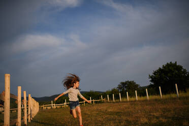 A happy little girl having fun and running outdoors in farm - HPIF06957