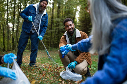 A diverse group of happy volunteers cleaning up forest from waste, community service concept. - HPIF06964