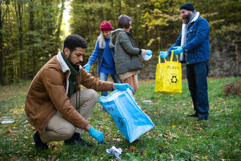 A diverse group of volunteers cleaning up forest from waste, community service concept - HPIF06968