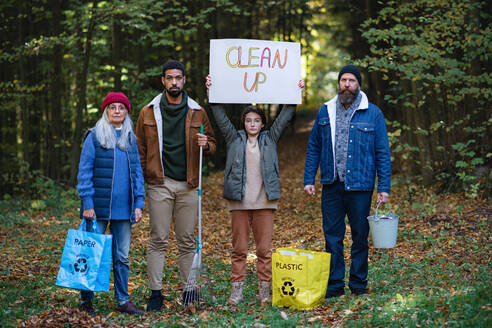 A diverse group of irritated activists ready to clean up forest, holding banner and looking at camera. - HPIF06975