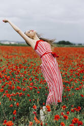 Young woman standing on tiptoes at poppy field - JJF00332