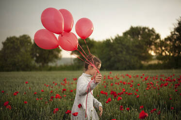 Mädchen geht mit Luftballons in einem Mohnfeld - ALKF00132