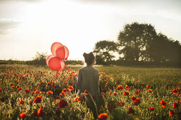 Mädchen geht mit Luftballons inmitten von Mohnblumen - ALKF00144