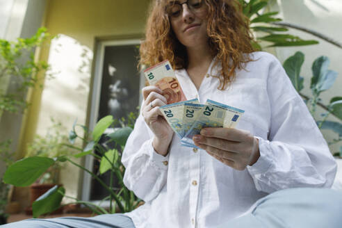 Frau beim Zählen von Papiergeld im Hinterhof - TYF00773