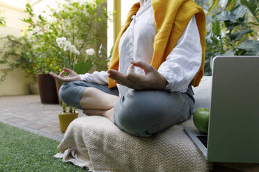 Freelancer meditating on crate at backyard - TYF00780