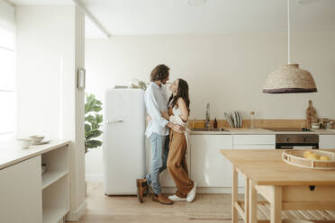 Happy couple standing together in kitchen at home - RCPF01703