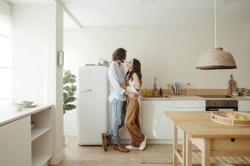 Glückliches Paar steht zusammen in der Küche zu Hause - RCPF01703