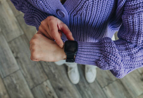 Frau mit lilafarbenem Pullover prüft die Zeit auf einer intelligenten Uhr - VSNF00558