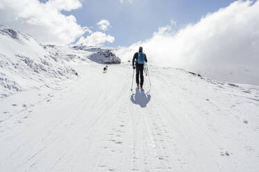 Mann zu Fuß mit Rucksack und Skistöcken an einem sonnigen Tag - PGF01469