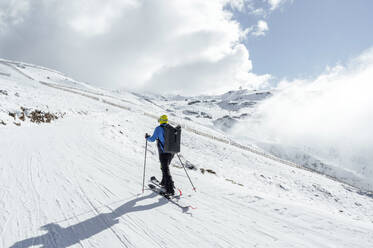 Mann mit Rucksack und Skiern geht auf Schnee - PGF01472