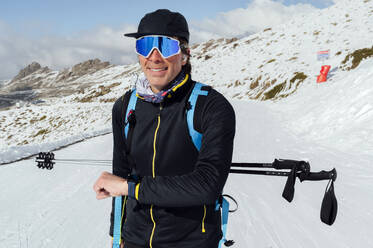 Glücklicher Mann mit Skibrille im Schnee stehend - PGF01474