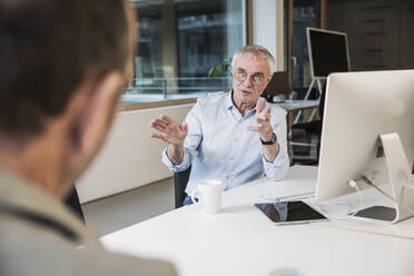 Businessman explaining colleague at office - UUF28264