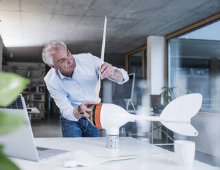 Ingenieur bei der Montage eines Flügels an einem Windradrotor im Büro - UUF28277