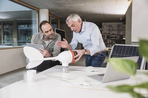 Ingenieur diskutiert gemeinsam im Büro über den Rotor einer Windkraftanlage - UUF28280