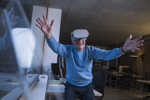 Glücklicher Geschäftsmann mit Virtual-Reality-Headset im Büro - UUF28312