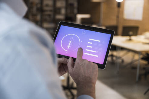 Geschäftsmann, der eine Automatisierungsanwendung auf einem Tablet-PC im Büro nutzt - UUF28357