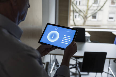 Geschäftsmann mit Tablet-PC, der eine Hausautomatisierungs-App im Büro zeigt - UUF28360