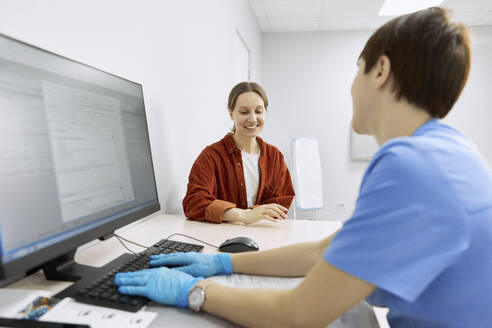 Smiling patient discussing with ophthalmologist at clinic - SANF00039