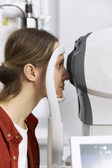 Patient doing eye check up through modern equipment at medical clinic - SANF00049