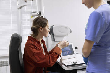 Patientin betrachtet die medizinischen Ergebnisse nach einer Untersuchung in der Klinik - SANF00054