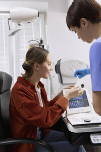 Doctor discussing with patient looking at medical results in clinic - SANF00055