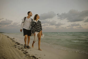 Man and woman walking together near shore at beach - IEF00281