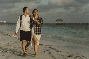 Boyfriend and girlfriend walking on sand at beach - IEF00292