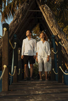Junges Paar steht zusammen auf einem Strohdach an der Strandpromenade - IEF00294