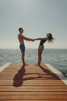 Mann hält die Hände einer Frau, die an einem sonnigen Tag am Pier steht - IEF00309