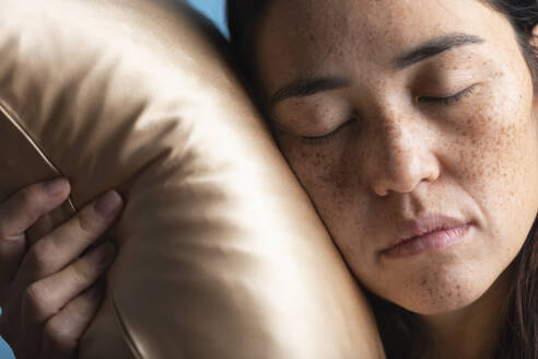 Woman with eyes closed sleeping on silk pillow - MRAF00929