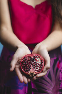 Hands of woman holding pomegranate fruit - MRAF00936
