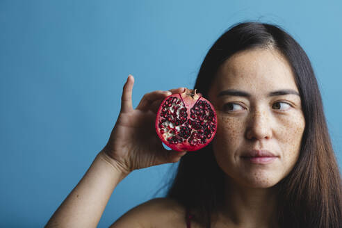 Woman with pomegranate against blue background - MRAF00937