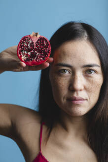 Woman with freckles on face holding pomegranate fruit - MRAF00938