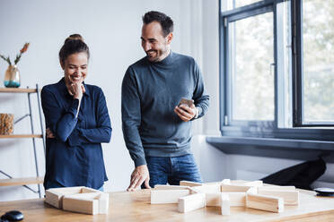 Happy business colleagues with wooden blocks on desk - JOSEF17452