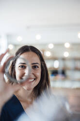 Lächelnde Geschäftsfrau, die in einem Büro kreisförmige Geräte durchsieht - JOSEF17484