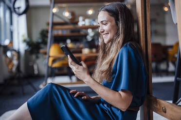 Smiling businesswoman using mobile phone in office - JOSEF17493