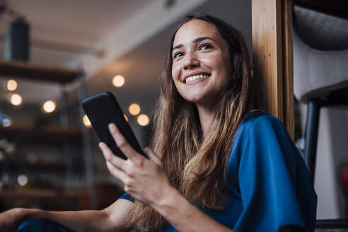 Glückliche Geschäftsfrau mit Smartphone im Büro - JOSEF17494