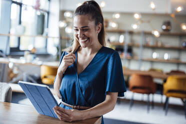 Happy businesswoman using tablet PC at desk - JOSEF17506