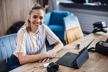Glückliche Frau mit Tablet-PC sitzt am Schreibtisch im Büro - JOSEF17527