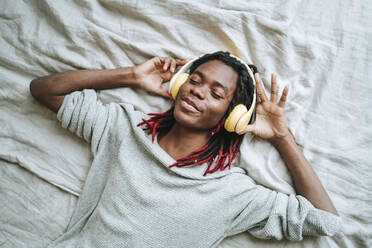 Young man with eyes closed lying on bed at home - MDOF00761