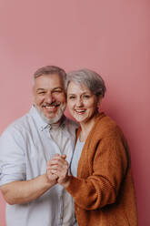 Glückliches reifes Paar steht vor rosa Hintergrund - MDOF00781