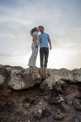 Lächelndes junges Paar steht am Rande einer Klippe - FBAF02111