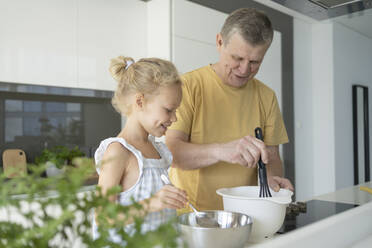Grandfather and granddaughter preparing food in kitchen at home - SVKF01316
