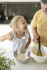 Glückliches Mädchen bei der Zubereitung von Essen mit Großvater in der Küche zu Hause - SVKF01318